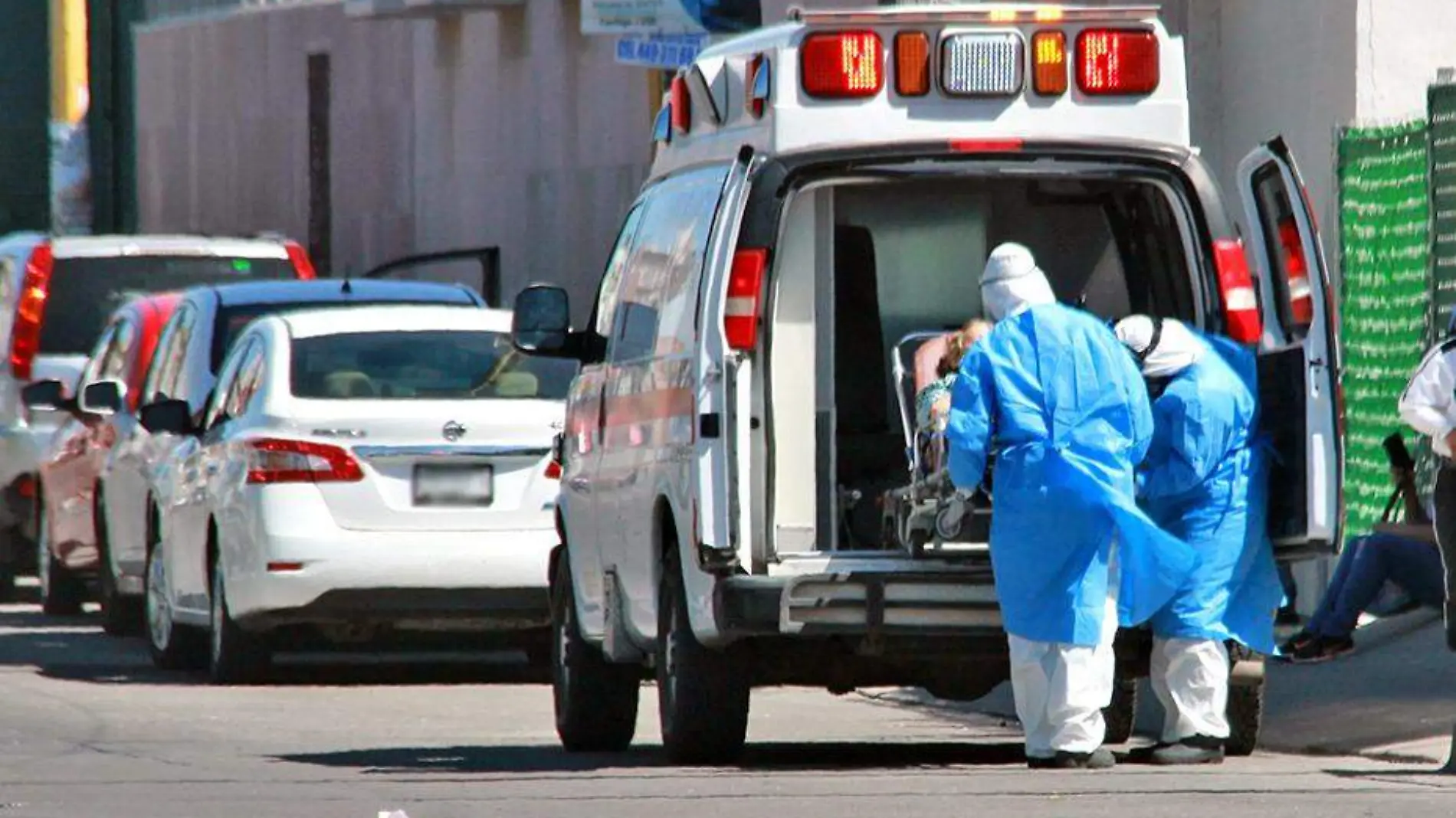 personal con indumentaaria anticovid sube paciente a ambulancia